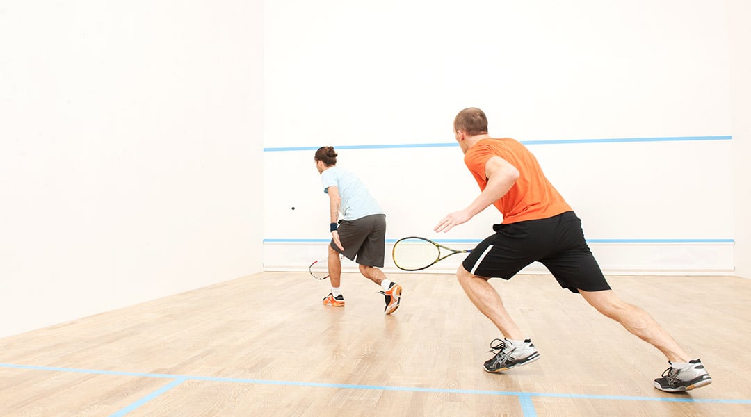 two Male Squash players serving